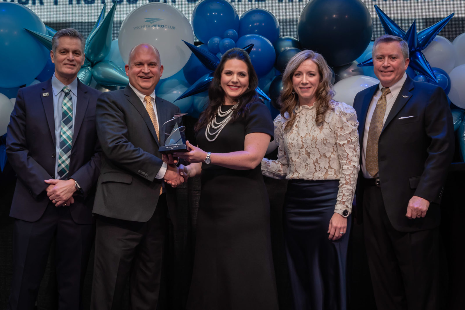 Dr. Rick Muma, Wichita State University President; Dr. John Tomblin, 2022 Trophy recipient; Ashley Bowen Cook, WAC Board Chair, Trophy Committee Chair and Greteman Group Vice President; Nicole Alexander, WAC President; John O’Leary, Airbus Americas Vice President of Engineering/Programs.